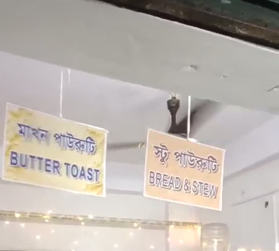 হাতে লেখা সাইনবোর্ড: মাখন পাউরুটি / BUTTER TOAST আর স্টু পাউরুটি / BREAD & STEW